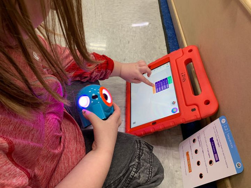 young girl using an ipad to program a robot